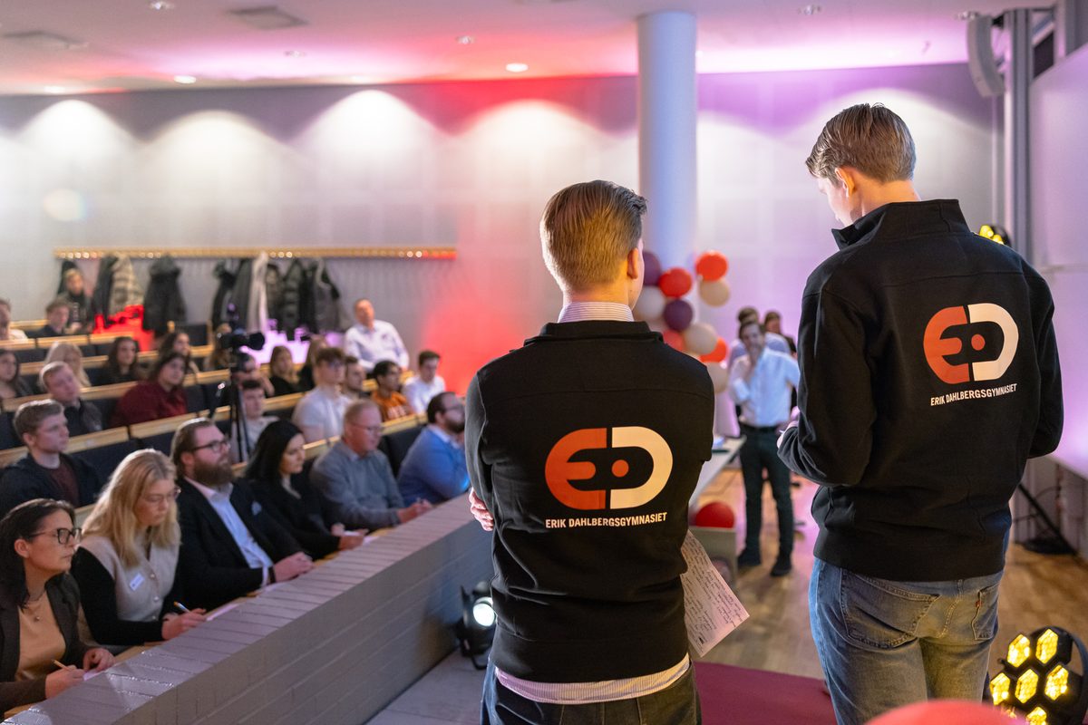 Två elever presenterar sitt lags lösning inför publiken i hörsalen