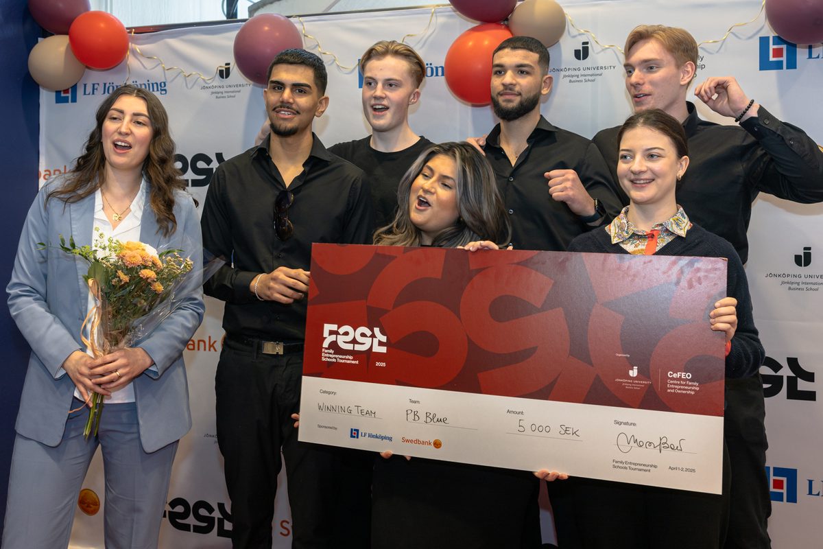 Det vinnande laget jublar med sin check och blommor framför sponsorväggen